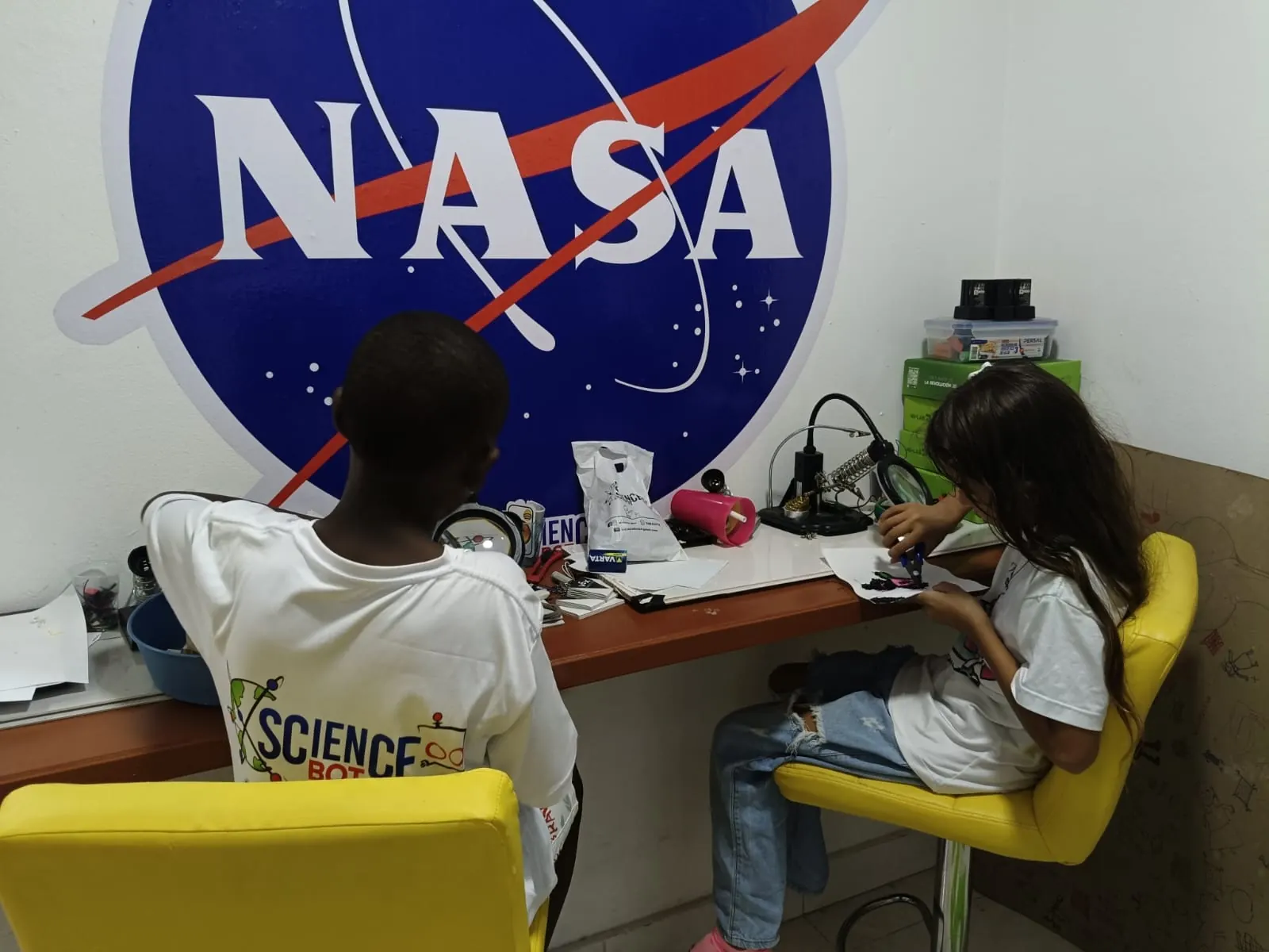 Estudiantes trabajan bajo el mural de la NASA en el aula de ScienceBot
