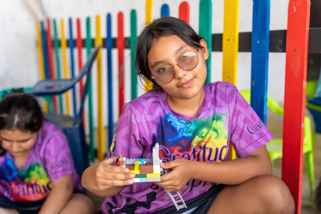 Joven muestra su robot de piezas en un taller