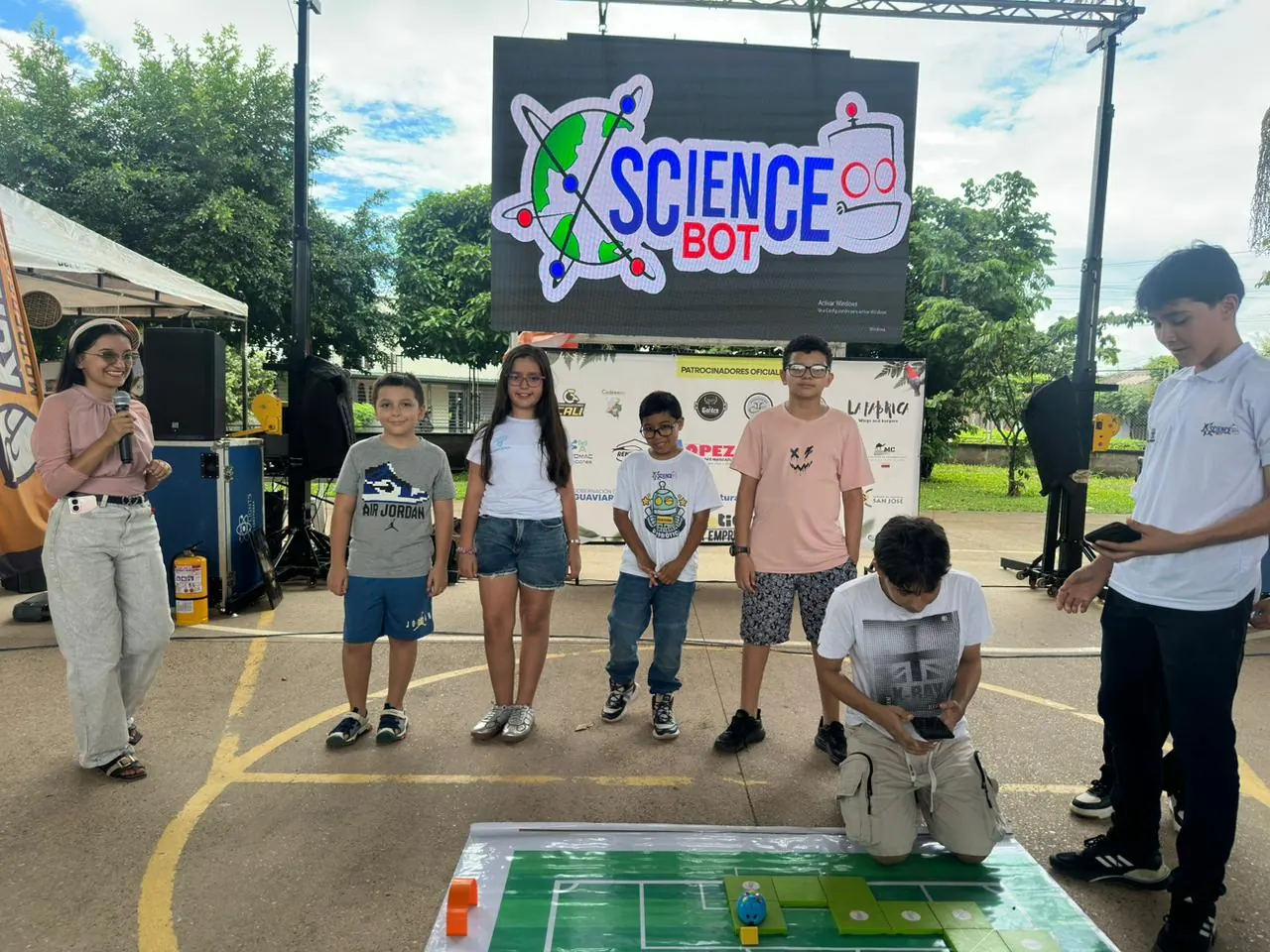 Jóvenes compiten en una cancha de fútbol robótico frente al público