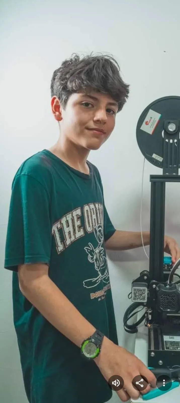 Joven junto a una impresora 3D con su bobina de filamento