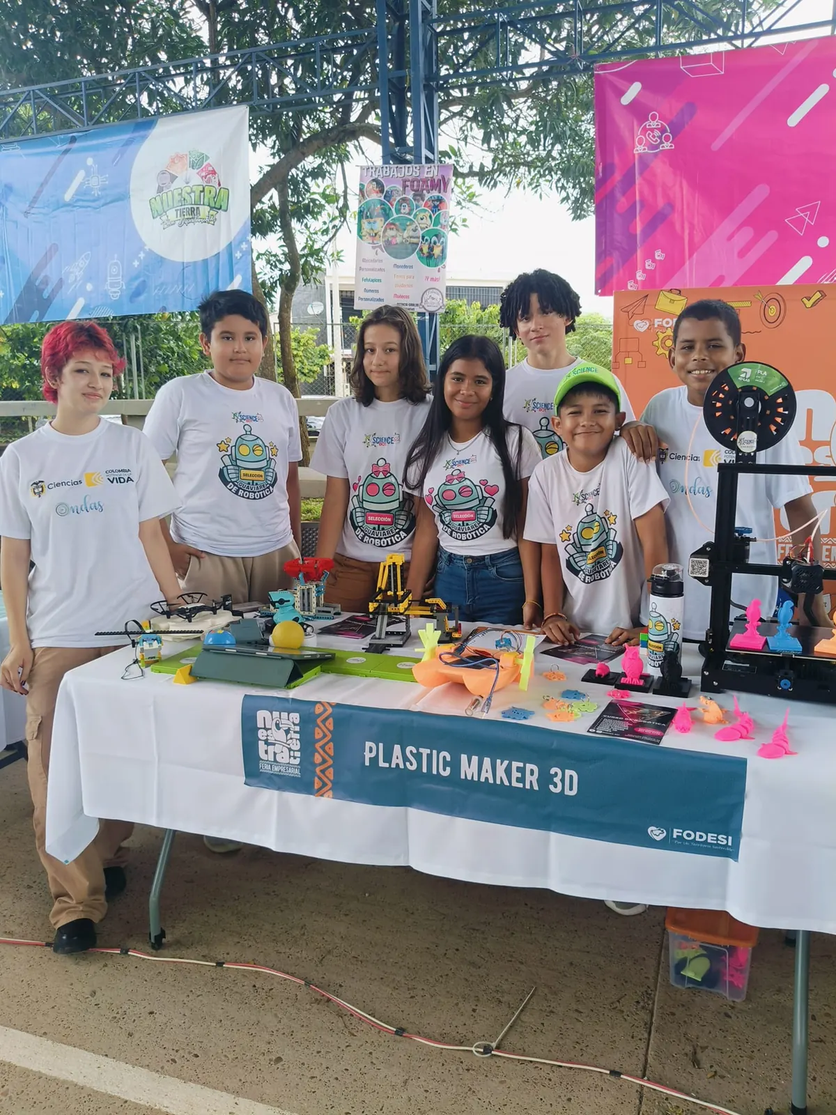Estudiantes de ScienceBot en el stand de Plastic Maker 3D, con impresora 3D y piezas sobre la mesa