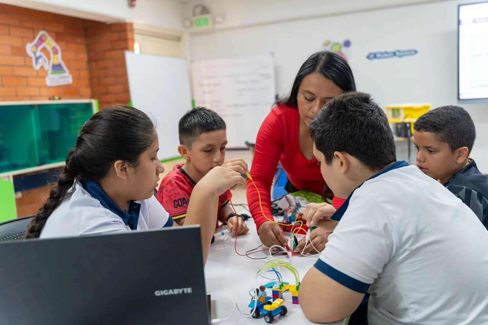 Docente acompaña a estudiantes que conectan un robot con cables