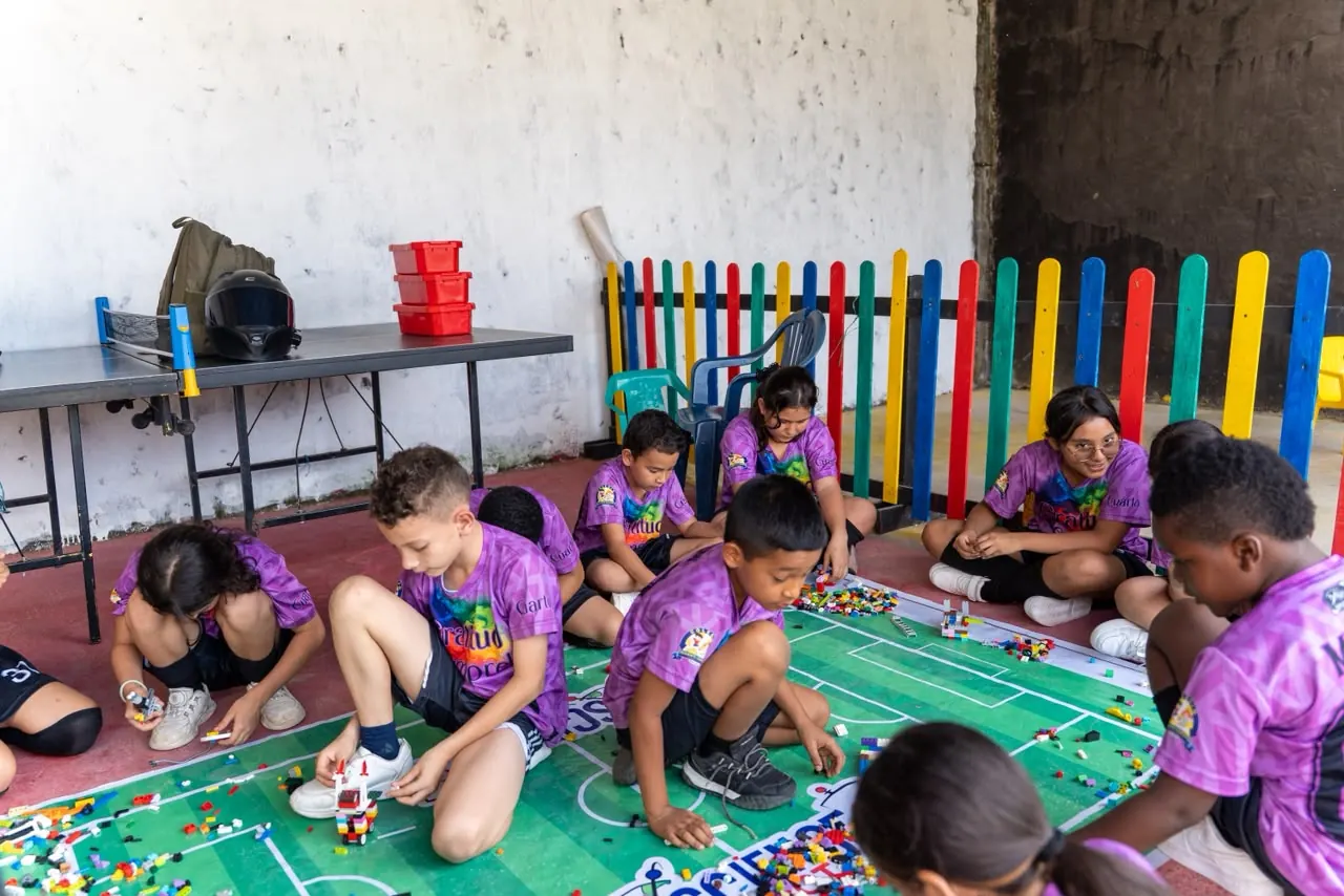 Niños arman robots en el piso durante un taller comunitario