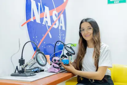 Tatiana Muñoz en el aula de ScienceBot, frente a un mural de la NASA